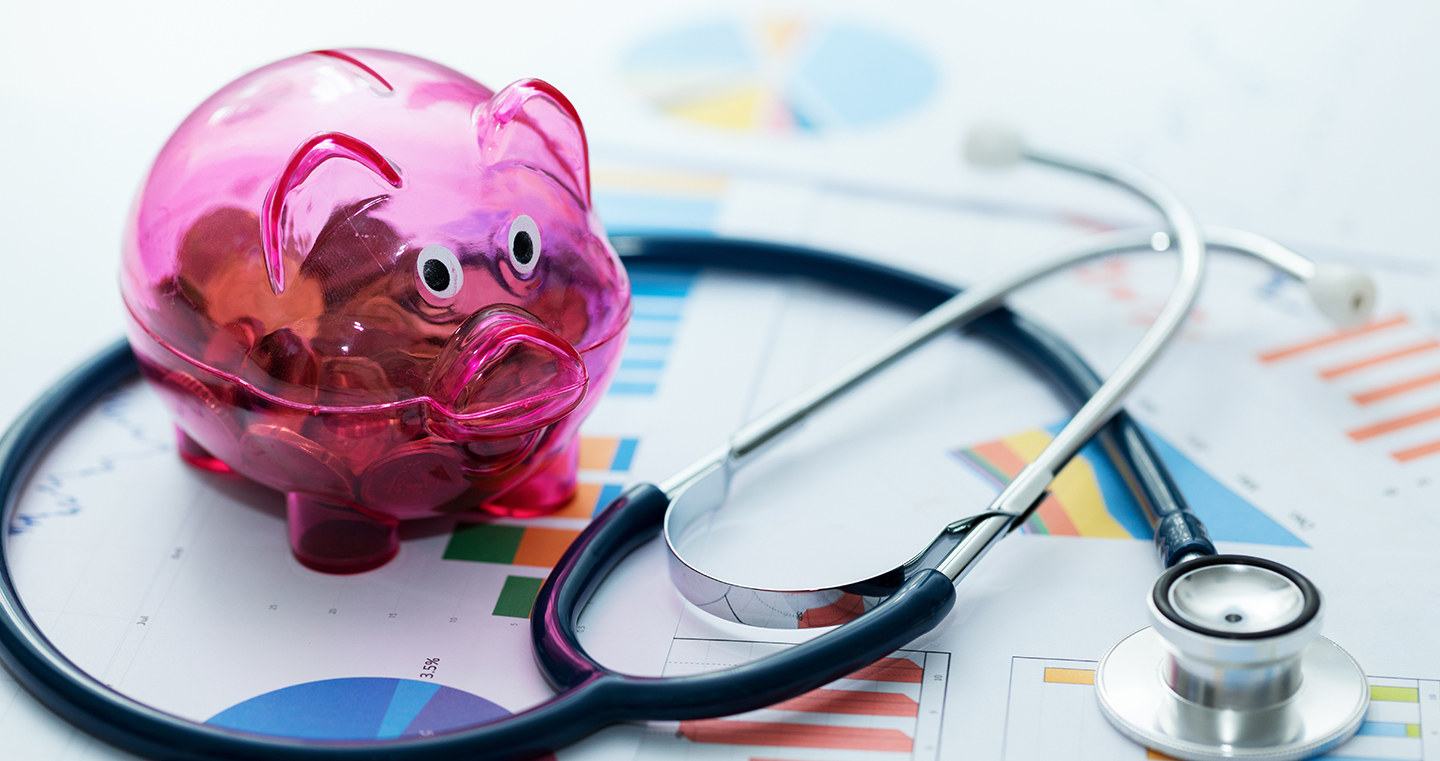 healthcare budget concept - stethoscope and piggy bank on graphic charts